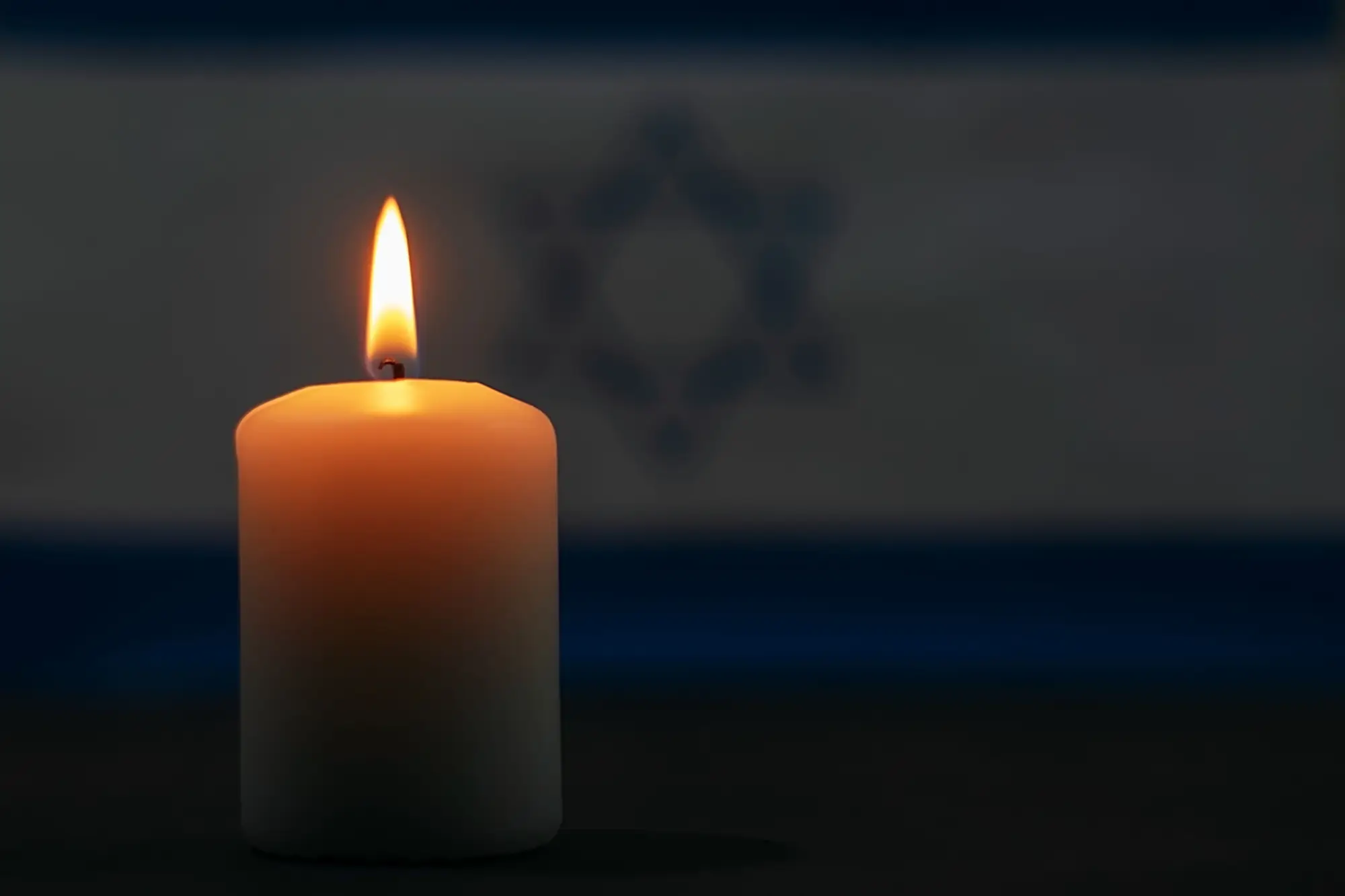 Yahrzeit candle burning with blurred star of David in background