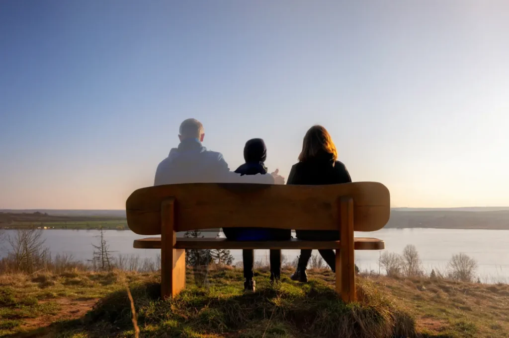 Family seated on a bench, the father is faded as if no longer with them